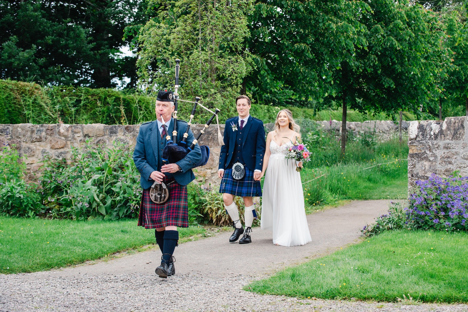 hochzeit-schottland-paar-im-park-mit-dudelsackspieler